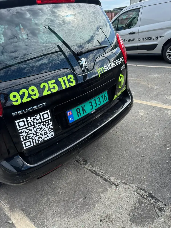 Bakluke på firmabil med stort telefonnummer, logo og QR-kode i grønt
