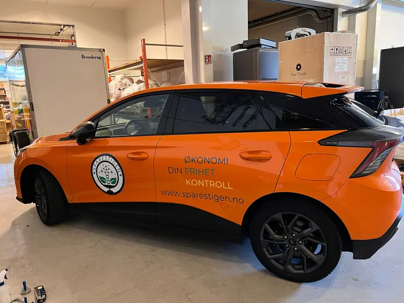 SUV foliert i oransje med logo og nettadresse på siden