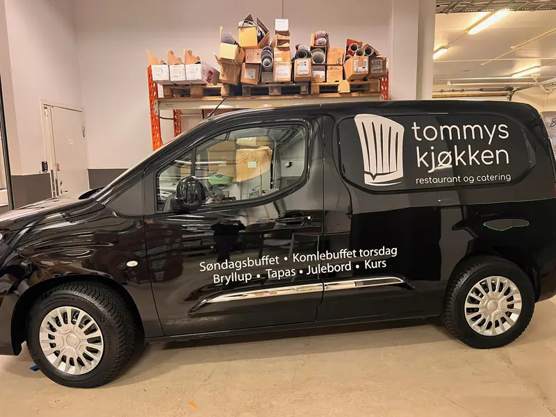 Sort varebil med logo på sidepanelet og tjenesteliste under