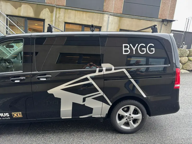 Sort varebil med hvitt grafisk motiv over sidepanel og skyvedør
