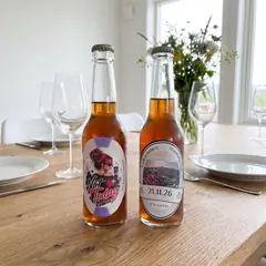 Flaskeetiketter med eget bilde: to ovale etiketter til dobbel bursdag på et dekket bord