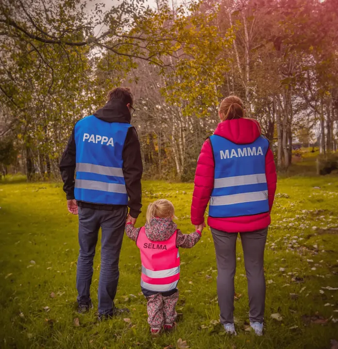 Familie bakfra i refleksvester med PAPPA, MAMMA og SELMA trykt på ryggen